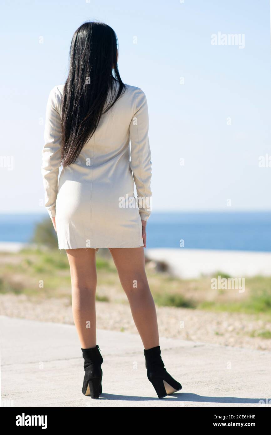 Vista posteriore di una giovane donna che indossa un abito corto e alto tacchi in piedi all'aperto Foto Stock