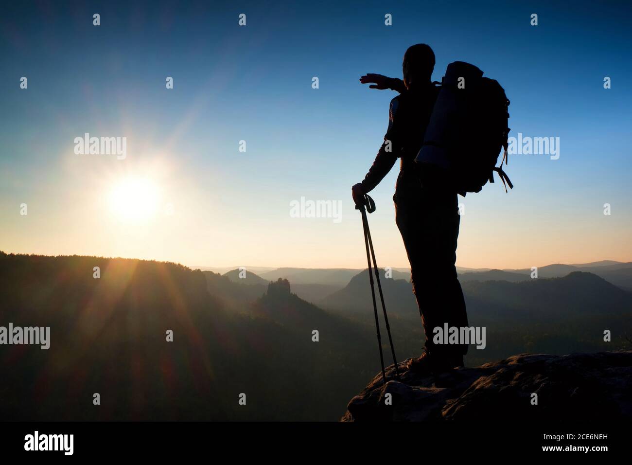 Silhouette affilata di un uomo alto sulla cima della montagna con il sole nella cornice. Guida turistica in montagna Foto Stock