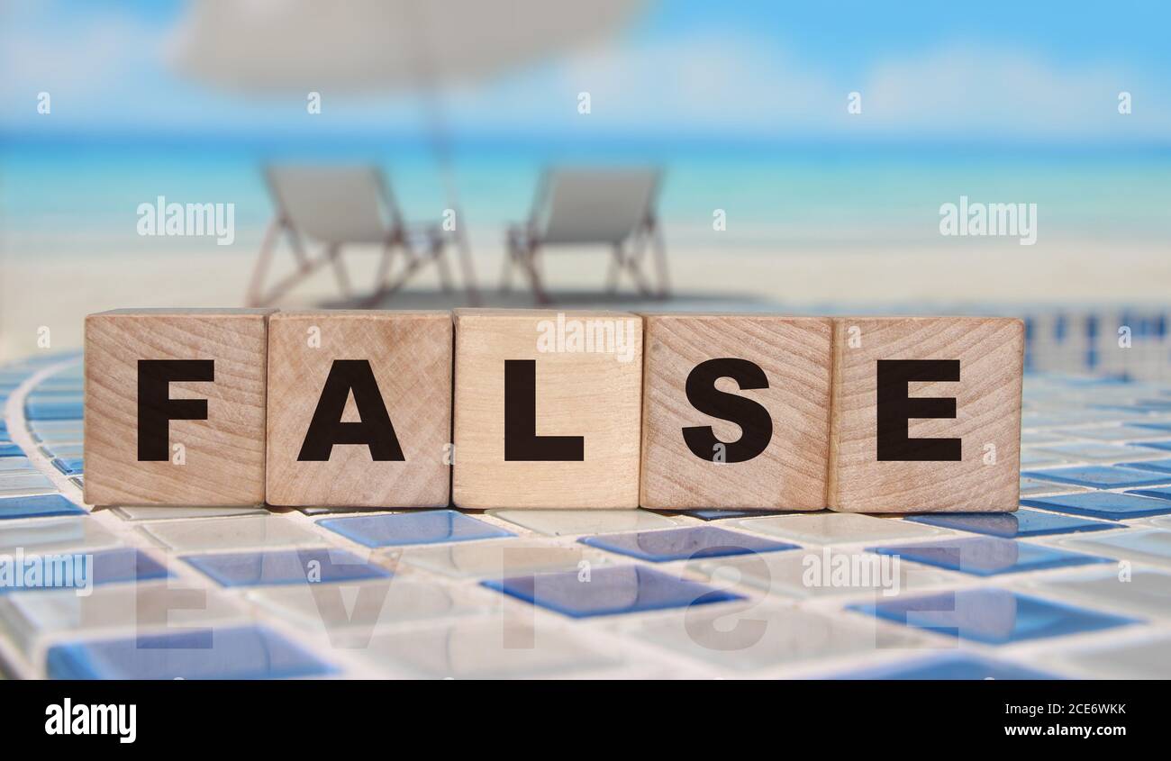 FALSE parole su cubi di legno vicino all'oceano. Concetto di affari di notizie falso o allineare Foto Stock
