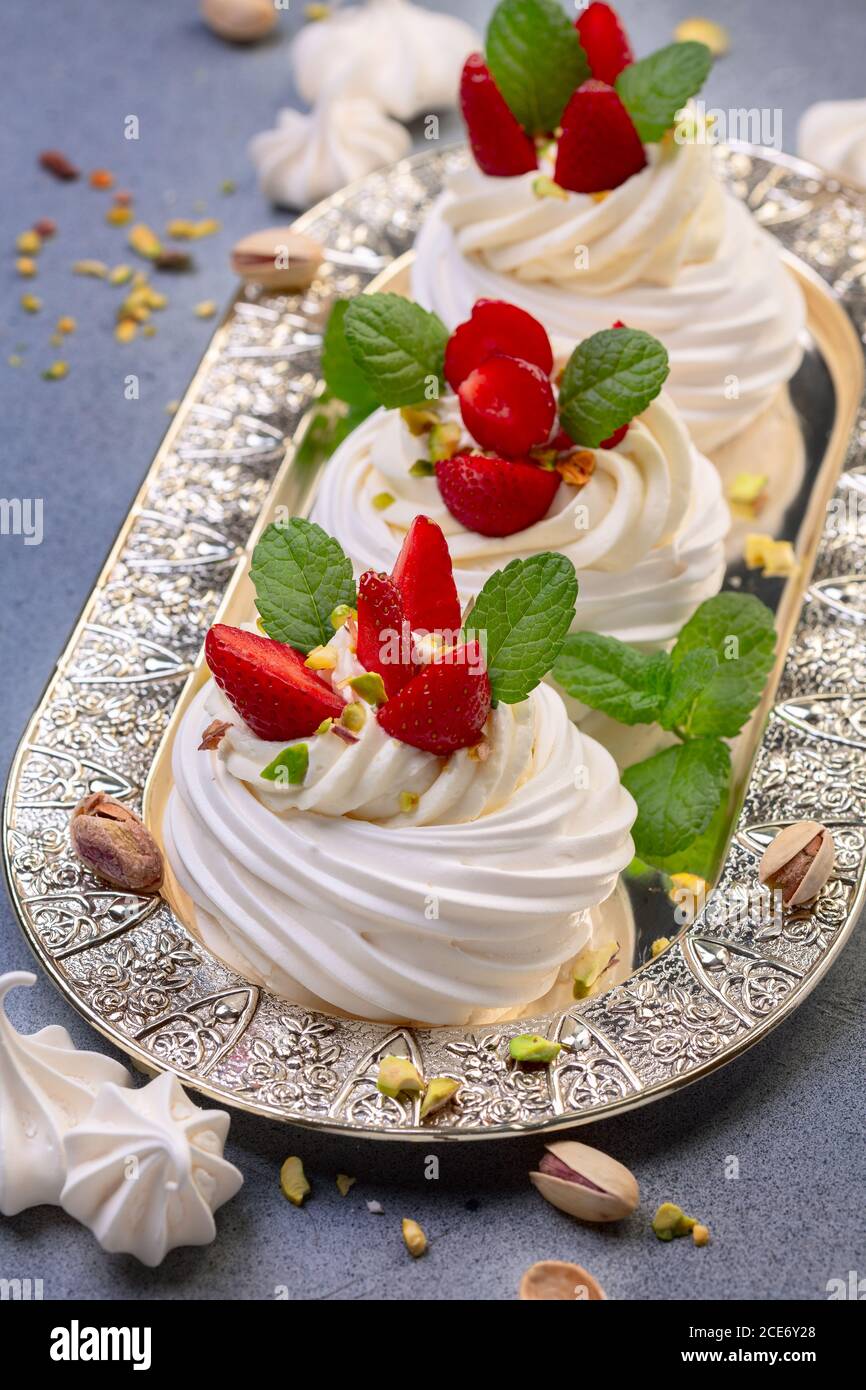 Delizioso dessert Pavlova meringa con fragole e pistacchi. Foto Stock