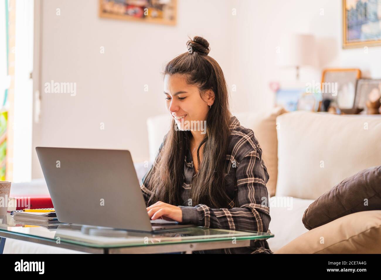 Giovane donna che lavora con il laptop in salotto Foto Stock