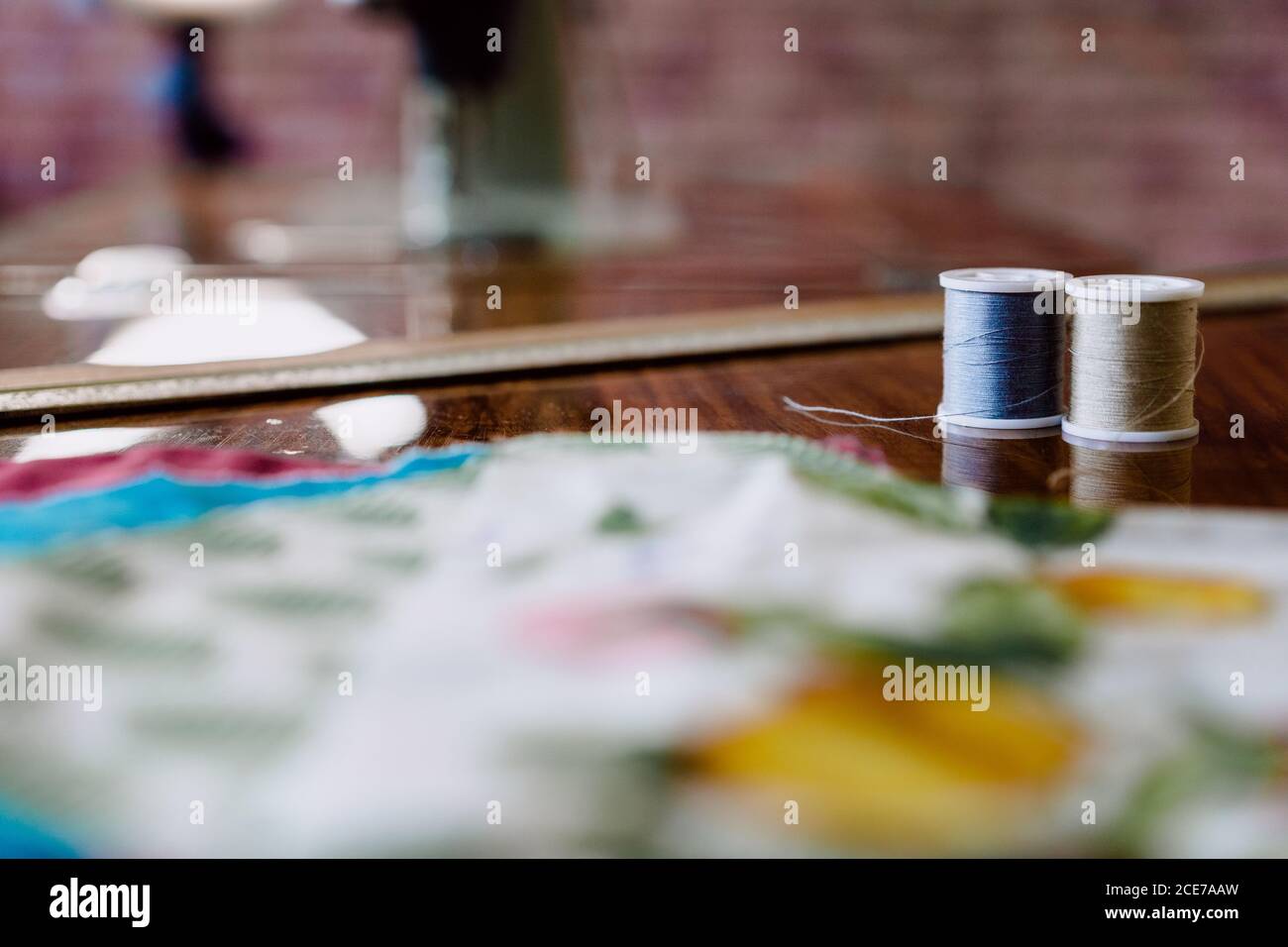 Bobine di fili sottili grigi e blu su tavolo di legno campioni tessili quasi morbidi con motivi in officina alla luce del giorno su sfondo sfocato Foto Stock