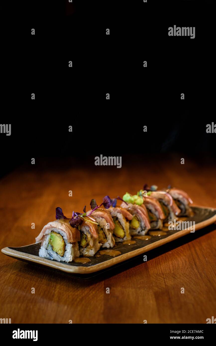 Closeup di set di panini con riso e pesce guarnito con erbe fresche e posto sul piatto nel ristorante Foto Stock