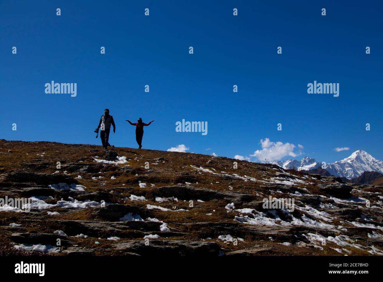 Due persone - un fotografo con la sua macchina fotografica e il suo modello sentire la gioia di vedere la bellezza paesaggistica dopo aver camminato su una collina con neve su rocce, clea Foto Stock