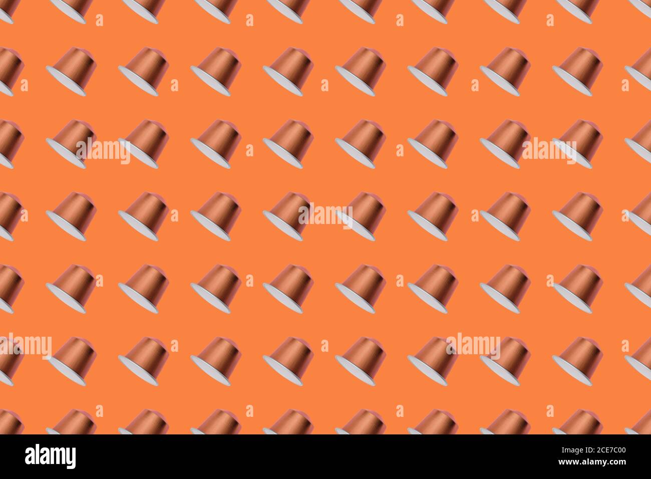 Vista dall'alto delle cialde di caffè dorate disposte in file uniformi come motivo senza giunture su sfondo arancione Foto Stock