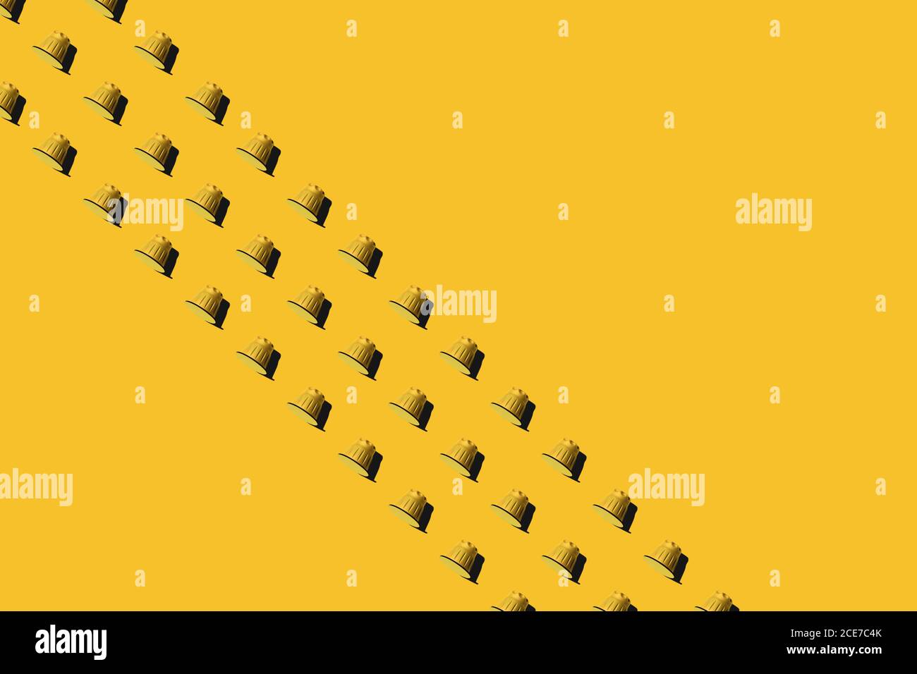 Vista dall'alto delle cialde di caffè gialle disposte in file uniformi come motivo senza giunture su sfondo giallo Foto Stock