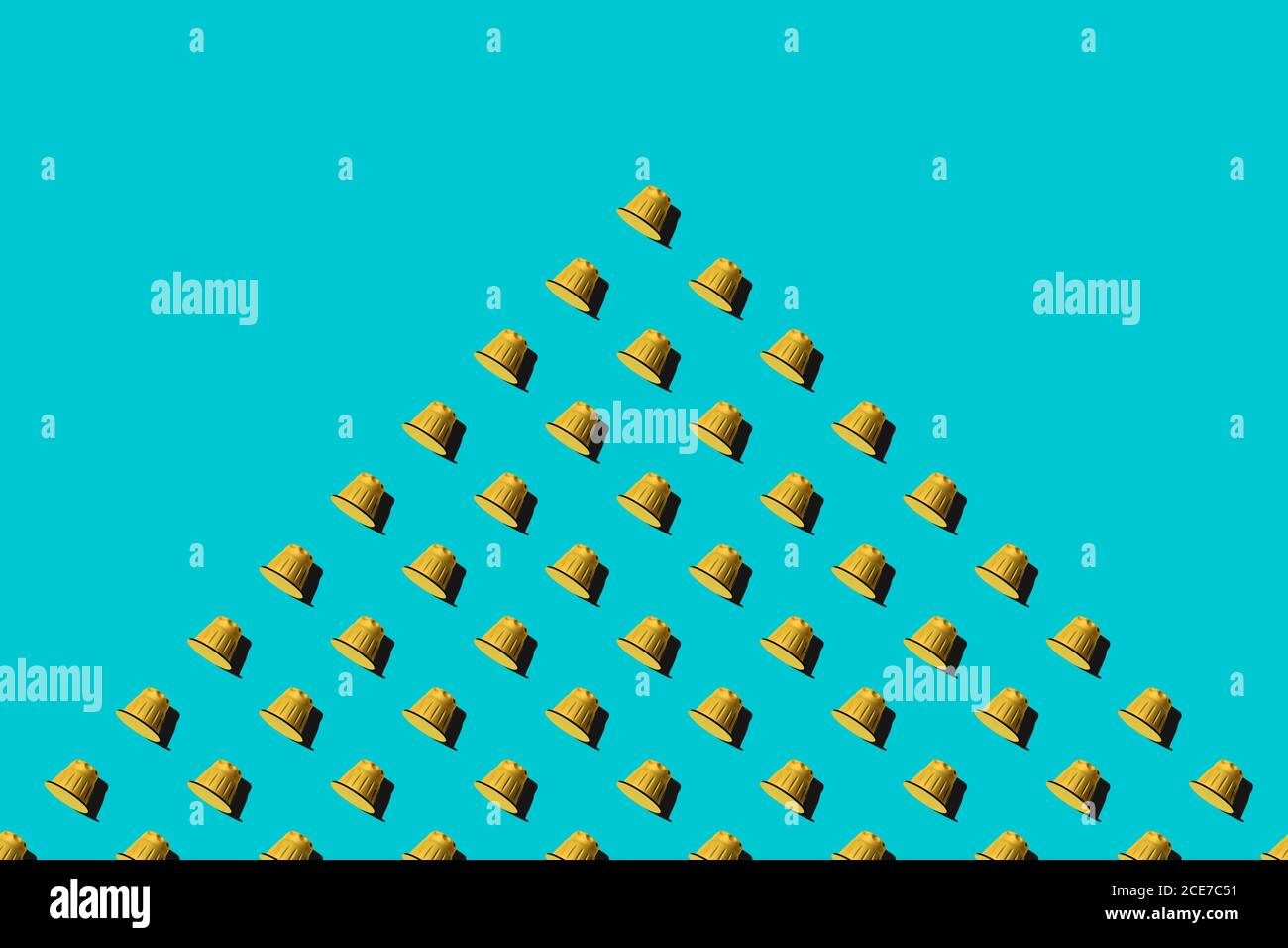 Vista dall'alto delle cialde di caffè gialle disposte in file uniformi come motivo senza giunture su sfondo blu Foto Stock