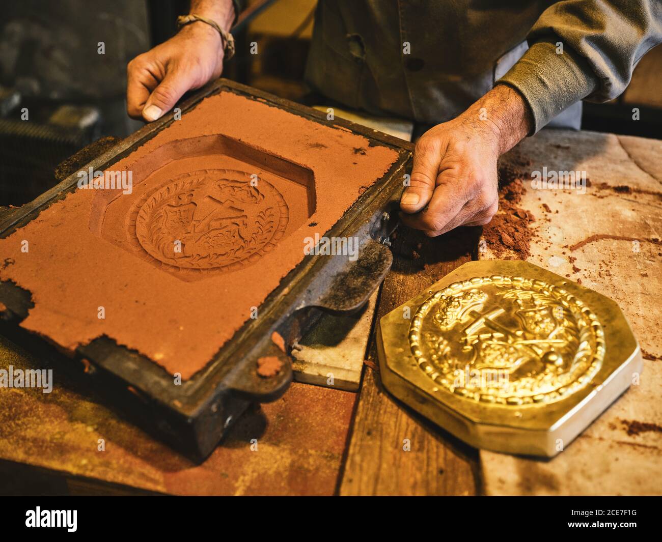 Raccolto orafo maschio irriconoscibile che mostra sabbia in scatola di stampaggio mentre preparazione dello stampo per l'alloggiamento in metallo in officina Foto Stock