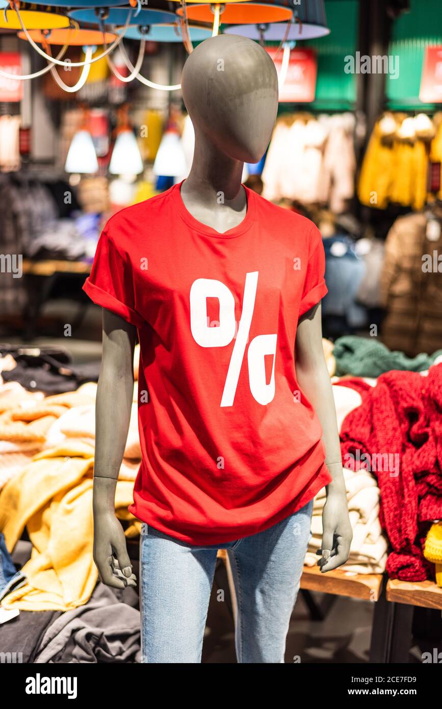 Manichino vestito in t-shirt rossa con segno percentuale e jeans blu nel centro commerciale. Vendita stagionale, shopping, consumerismo e concetto di moda. Foto Stock