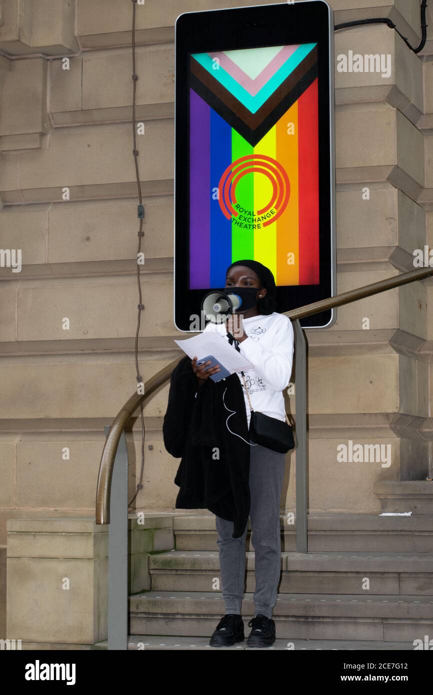 La ribellione dell'estinzione protesta fuori del Royal Exchange Theatre, Manchester, Regno Unito e donna con il megafono davanti al simbolo dell'orgoglio Foto Stock