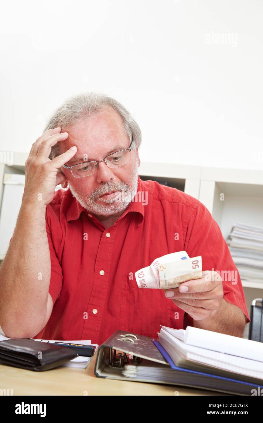 Il pensionato interessato guarda con attenzione alle banconote in euro in mano Foto Stock