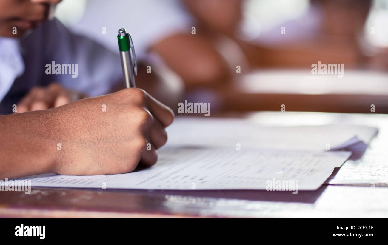 Mano degli studenti che scrivono e che prendono l'esame con stress in in aula Foto Stock