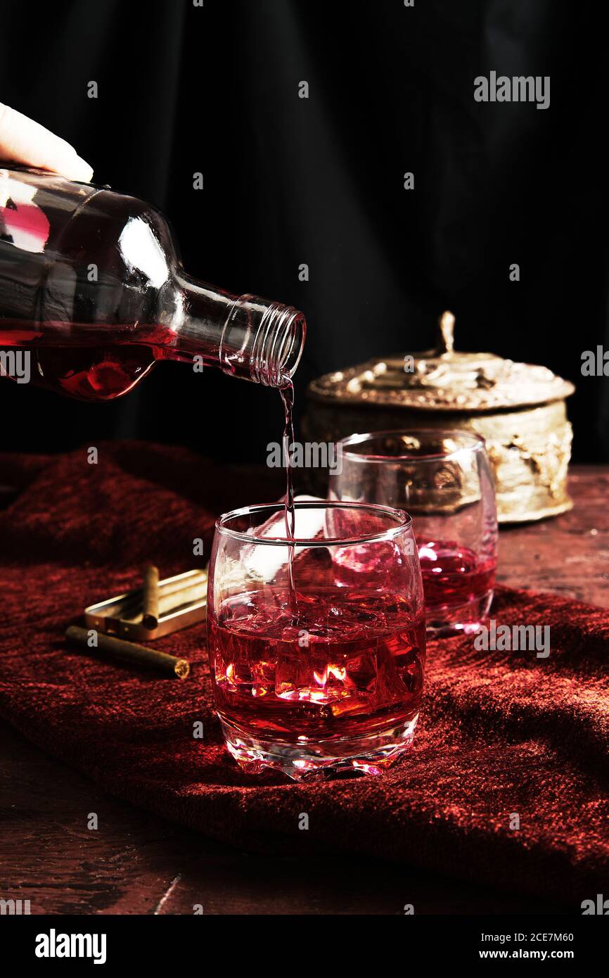 persona anonima che serve il whisky in un bicchiere Foto Stock