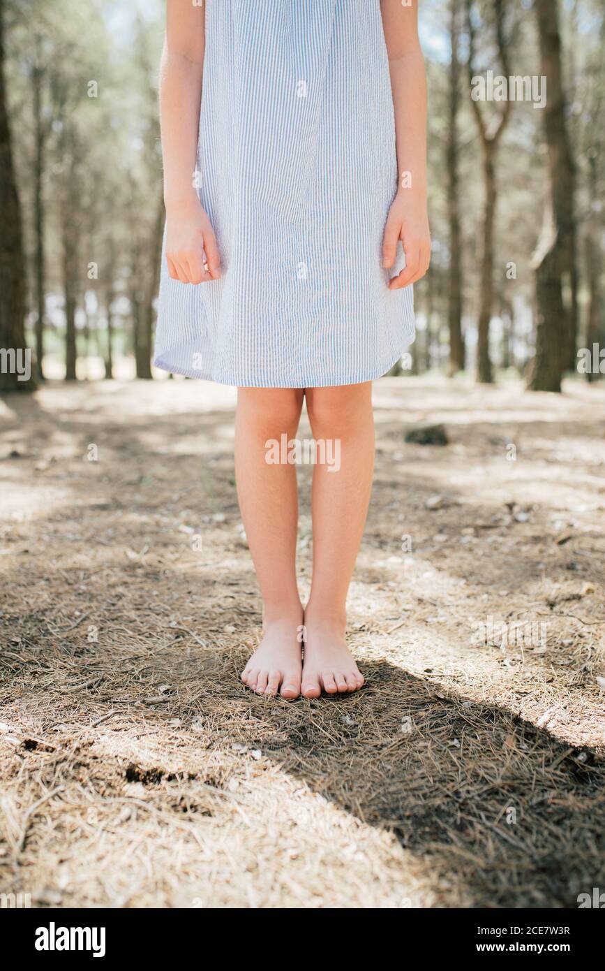 Crop irriconoscibile bambino a piedi nudi snello in un vestito blu pallido  in piedi su un terreno asciutto in vicolo in una giornata di sole in  campagna Foto stock - Alamy