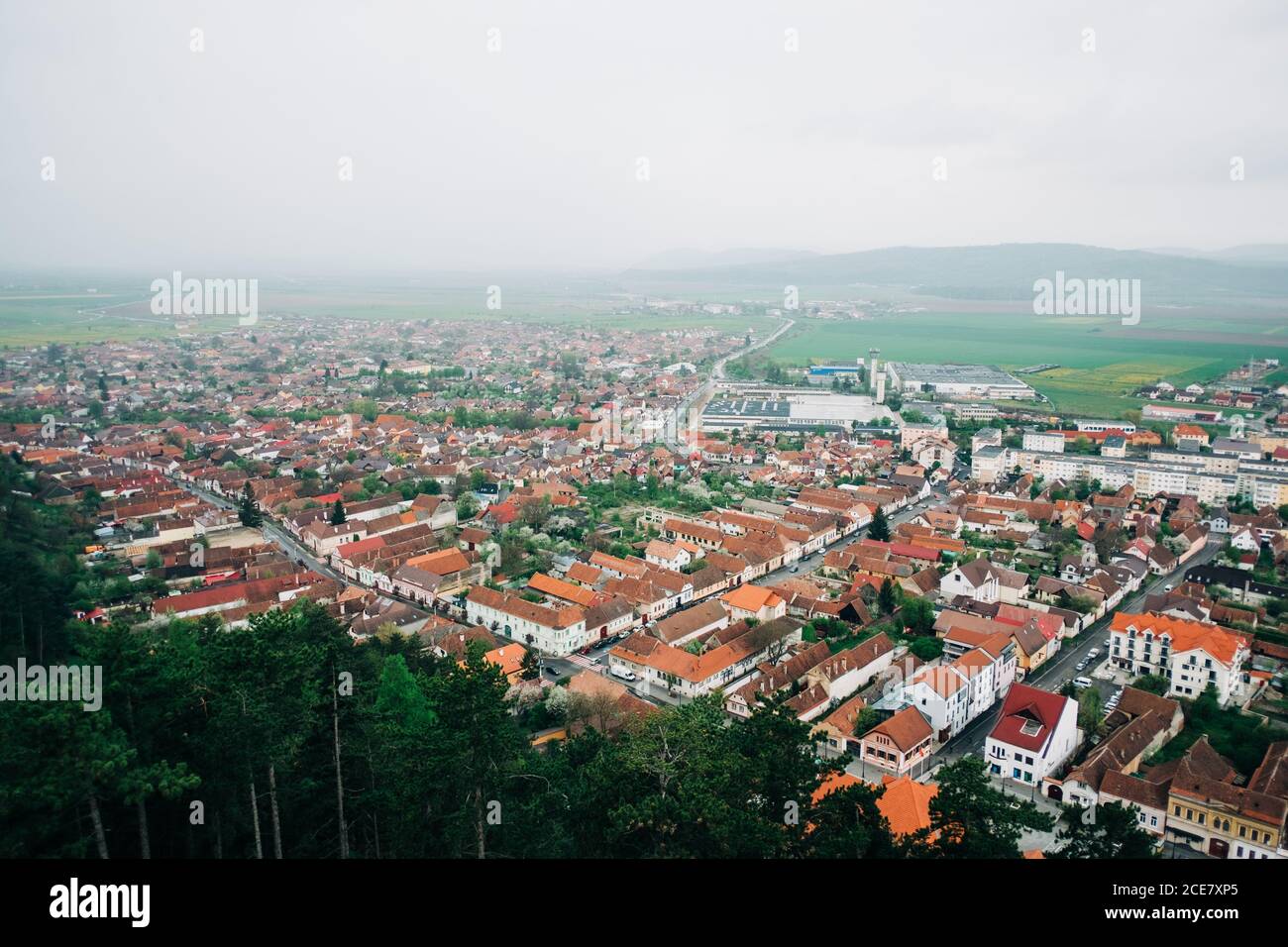 Da sopra vista panoramica della piccola città di San Giorgio in Transilvania con cottage accoglienti e circondato da verdi colline Foto Stock
