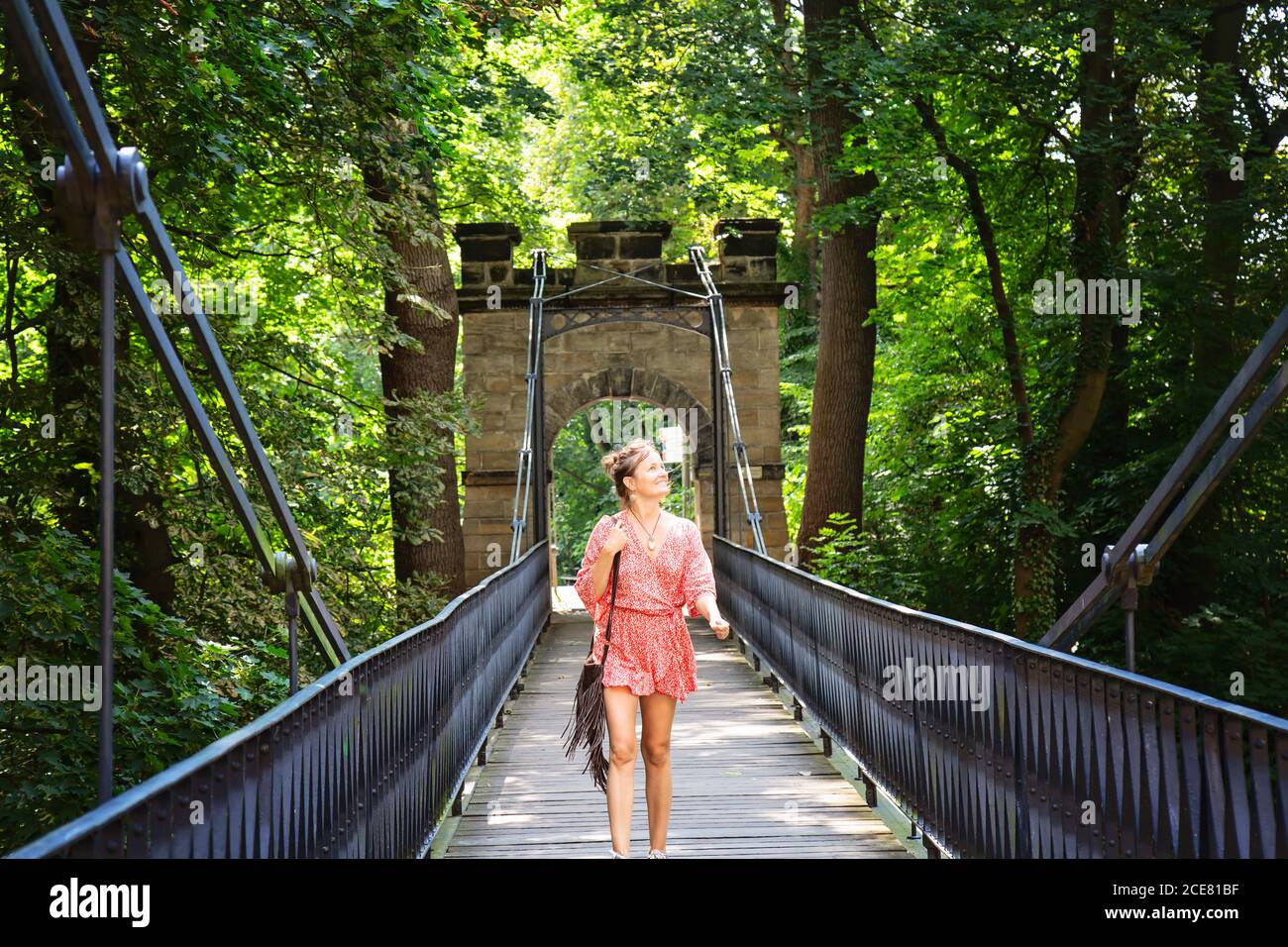 Donna in abito rosso che cammina sul ponte, castello Decin in Boemia Foto Stock