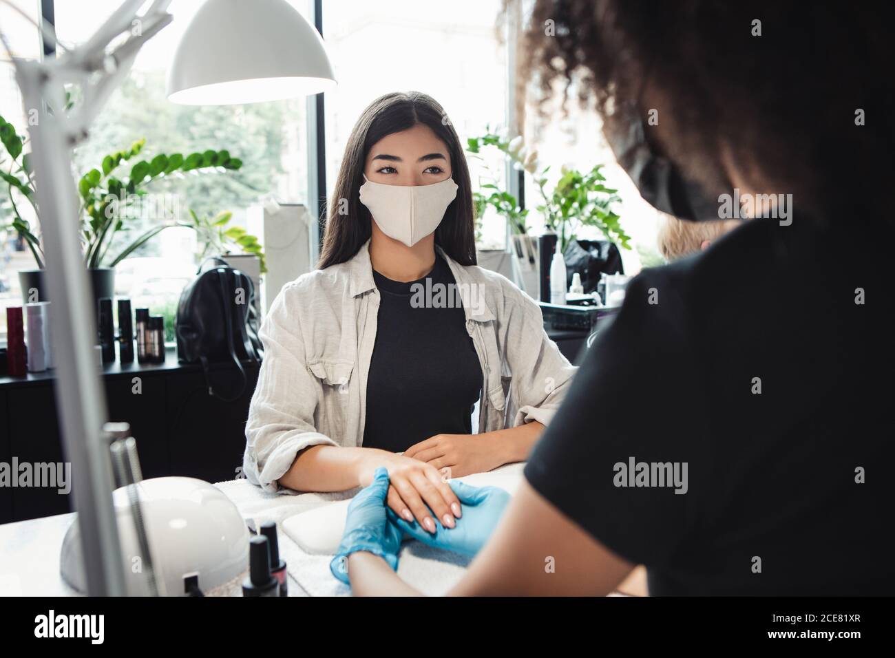 Riapertura a causa di pandemia, misure di sicurezza. Donna asiatica in maschera protettiva guarda master Foto Stock