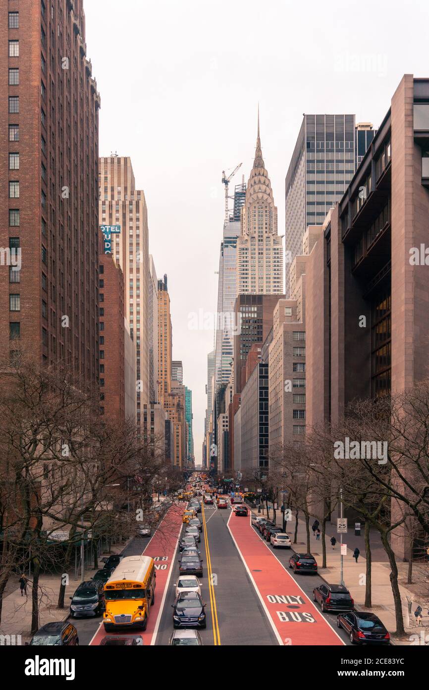 Città di New York con traffico di trasporto su strada dritta che conduce tra edifici alti e moderni in primavera sera Foto Stock