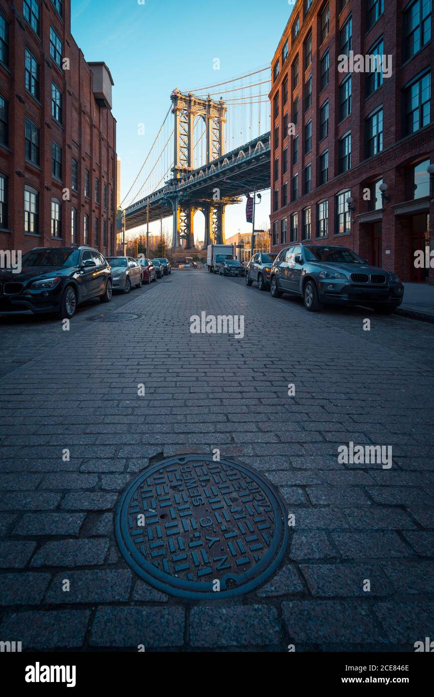 Ponte di Manhattan visto da una stretta strada lastricata del quartiere di Brooklyn Con vecchi edifici a New York City Foto Stock