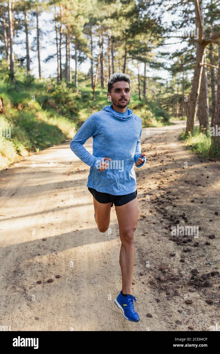 Uomo determinato che corre sulla natura durante l'allenamento Foto Stock