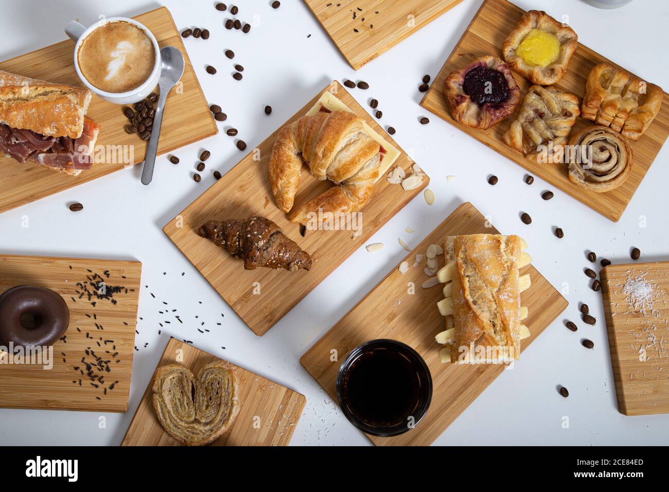 Vista dall'alto sul tavolo della colazione, ricco di pasticcini assortiti, panini e caffè serviti su tavole di legno Foto Stock