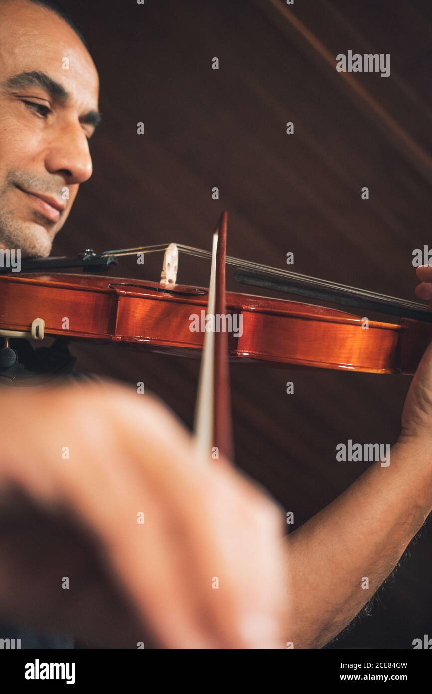 Dal basso talentuoso violinista ispanico maschile focalizzato suonando violino durante prova Foto Stock