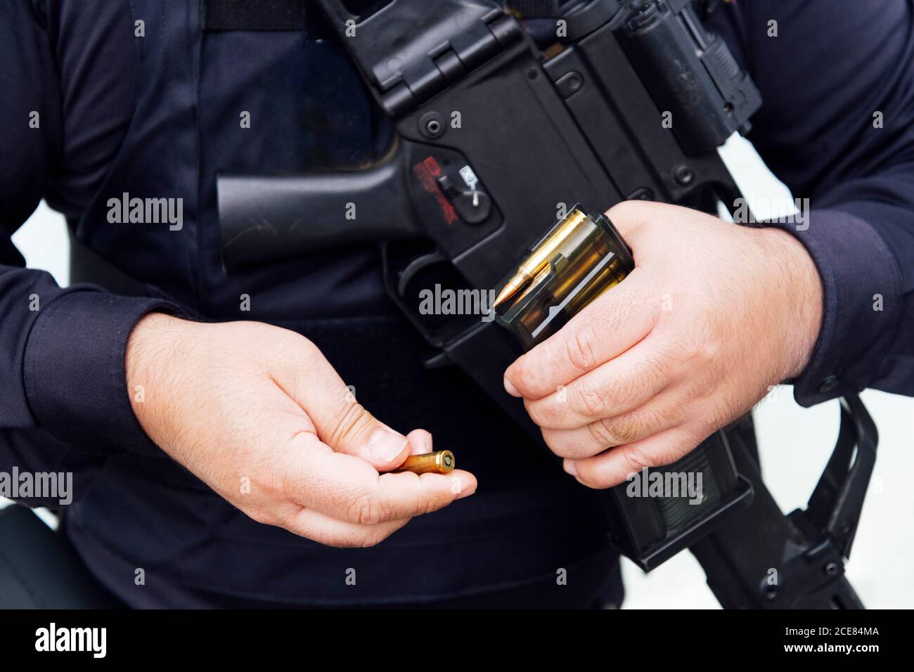 Crop chubby anonimo poliziotto in uniforme scura che mostra d'oro pallottola realizzata in piombo e ottone mentre si tiene l'arma da fuoco di luce diurna Foto Stock
