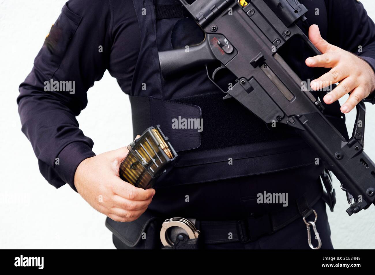 Crop chubby anonimo poliziotto in uniforme scura che mostra d'oro pallottola realizzata in piombo e ottone mentre si tiene l'arma da fuoco di luce diurna Foto Stock