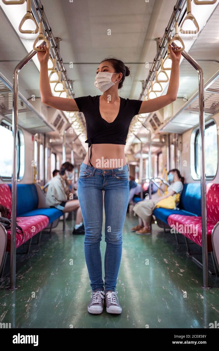 Donna etnica che indossa una maschera protettiva che viaggia in treno durante il coronavirus focolaio Foto Stock