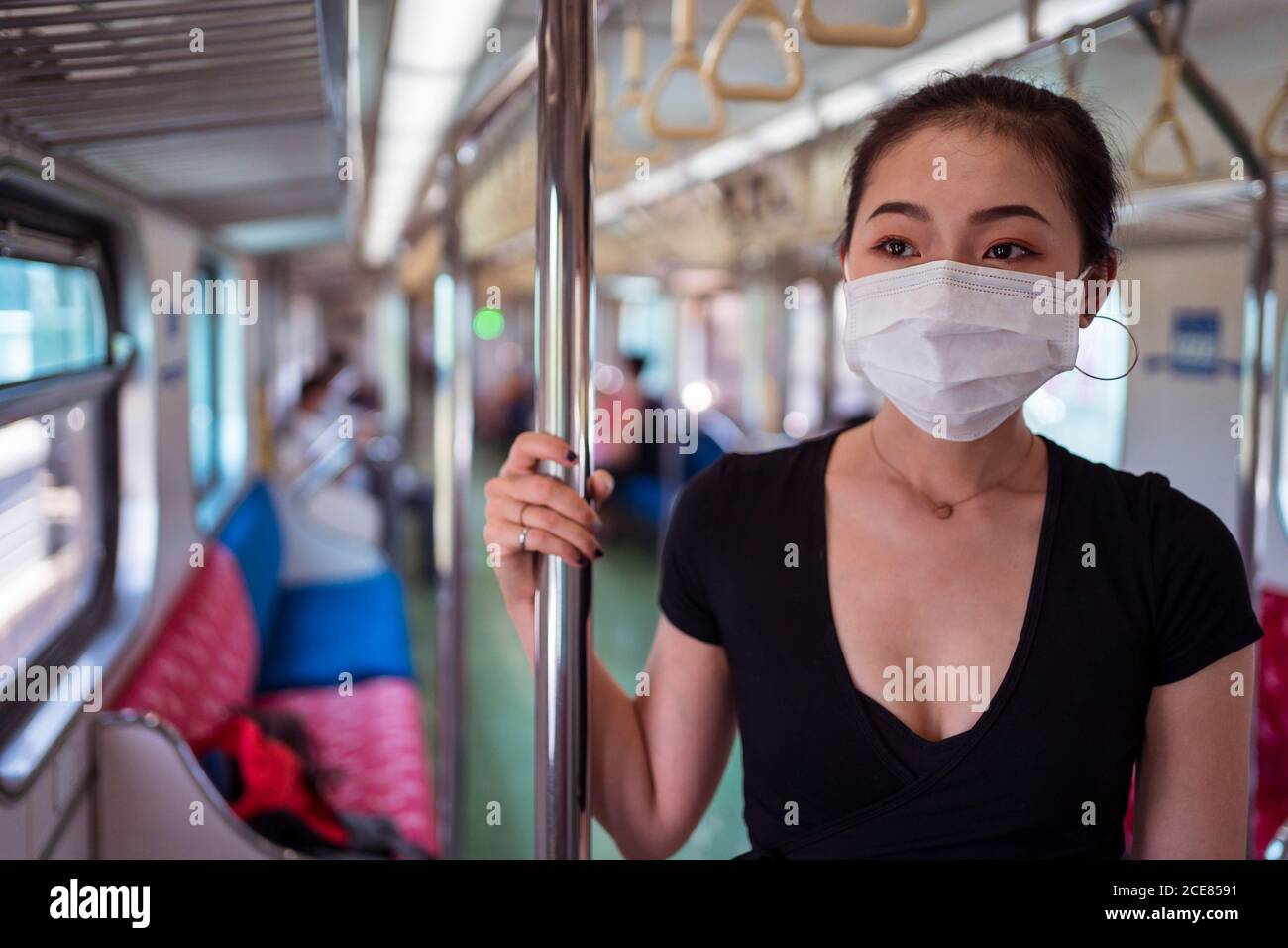 Donna etnica che indossa una maschera protettiva che viaggia in treno durante il coronavirus focolaio Foto Stock