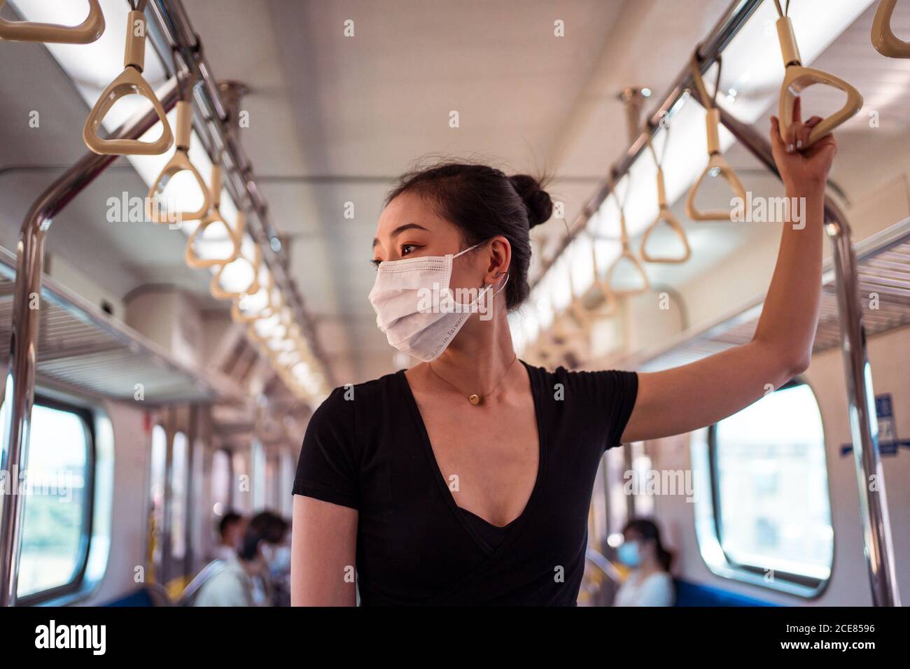 Donna etnica che indossa una maschera protettiva che viaggia in treno durante il coronavirus focolaio Foto Stock