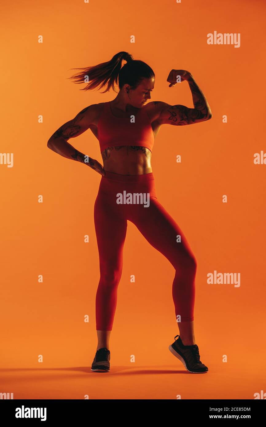 Ritratto di bodybuilder femminile che mostra bicipiti. Indossa la donna in un abbigliamento atletico che mostra il suo corpo muscolare. Foto Stock