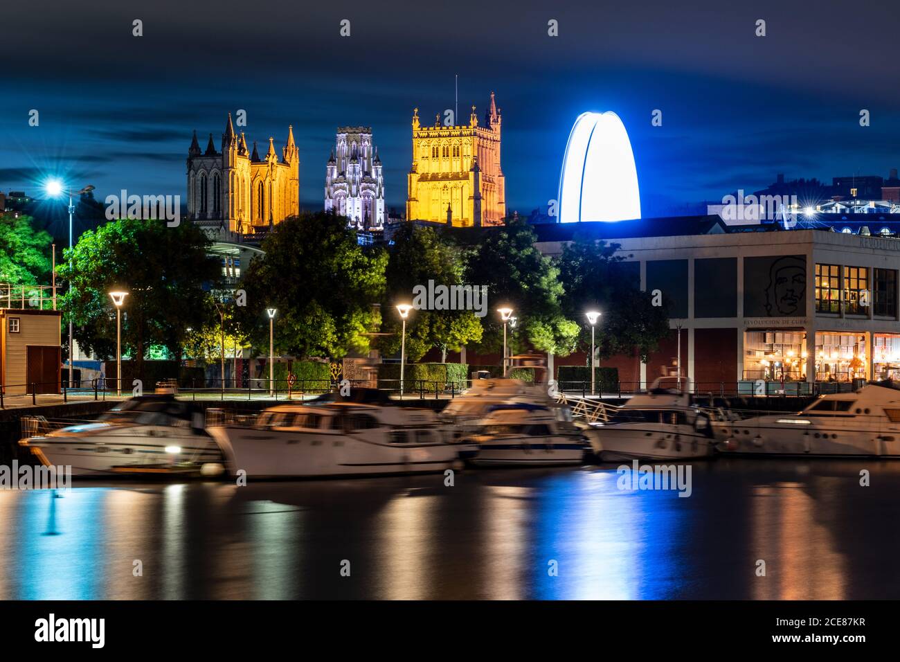 La Cattedrale di Bristol e la Torre Universitaria del Wills Memorial Building sono illuminate di notte sopra il porto galleggiante di Bristol. Foto Stock