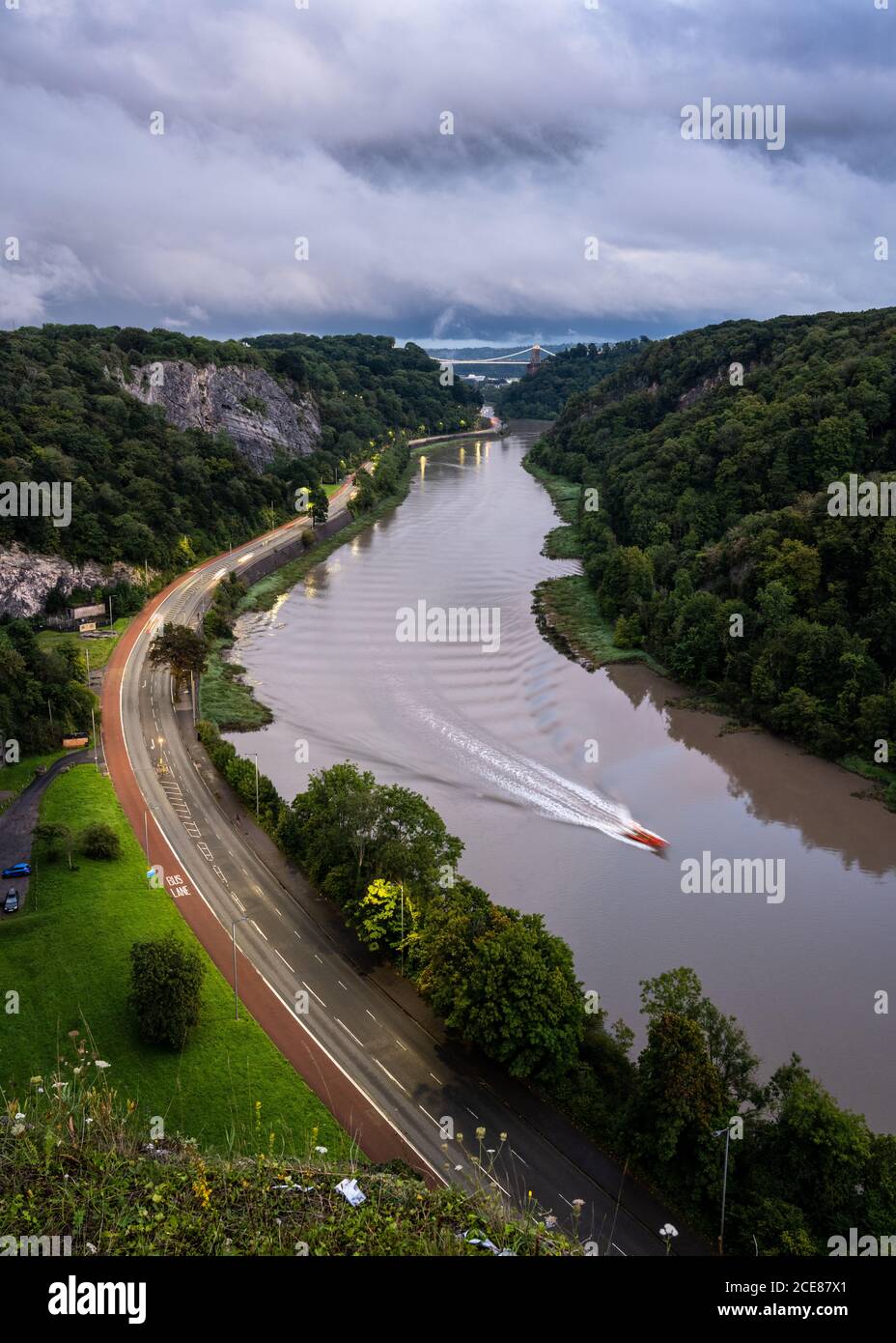 Una barca viaggia lungo l'estuario del fiume Avon in alta marea, sotto l'iconico Clifton Suspension Bridge nella gola Avon di Bristol. Foto Stock