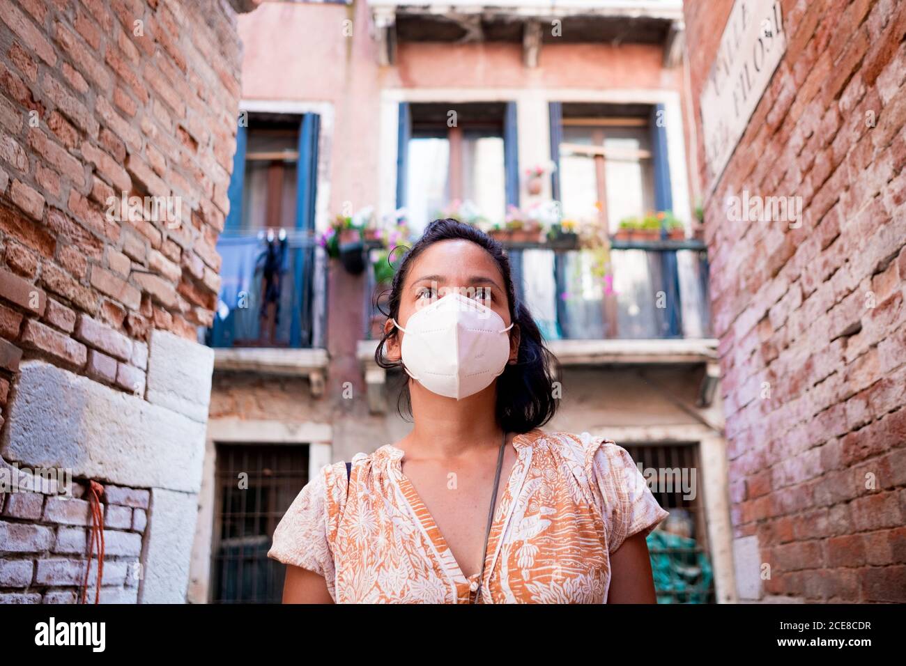 Giovane turista che indossa la maschera a piedi in una strada di Venezia in Italia. Viaggi e turismo industria durante la pandemia del virus della corona e covid19 di Foto Stock