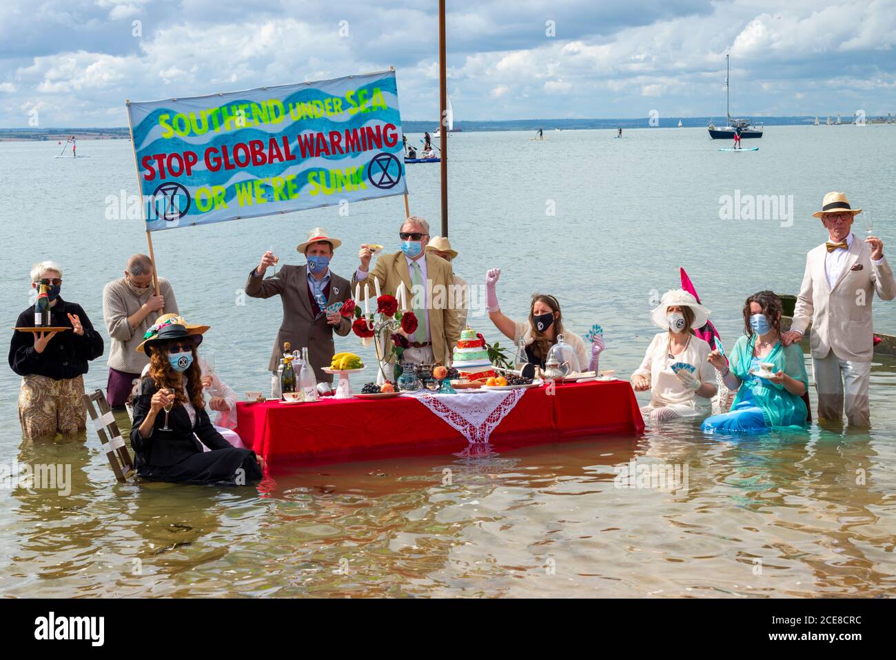 Southend on Sea, Essex, Regno Unito. 31 Agosto 2020. Il ramo locale della ribellione dell'estinzione ha organizzato un evento unico per simboleggiare le maree crescenti causate dal cambiamento climatico, istituendo un tavolo in mare per il tè pomeridiano mentre la marea entra nella località balneare. Vestito in stile edoardiano l'idea è quella di rappresentare la band che suona come Titanic Lavelli Foto Stock