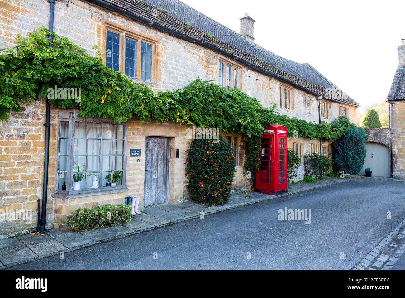 Un cottage con tetto di paglia costruito dalla pietra locale del prosciutto e una storica scatola telefonica rossa nel centro del villaggio di Montacute, Somerset, Inghilterra, Regno Unito Foto Stock