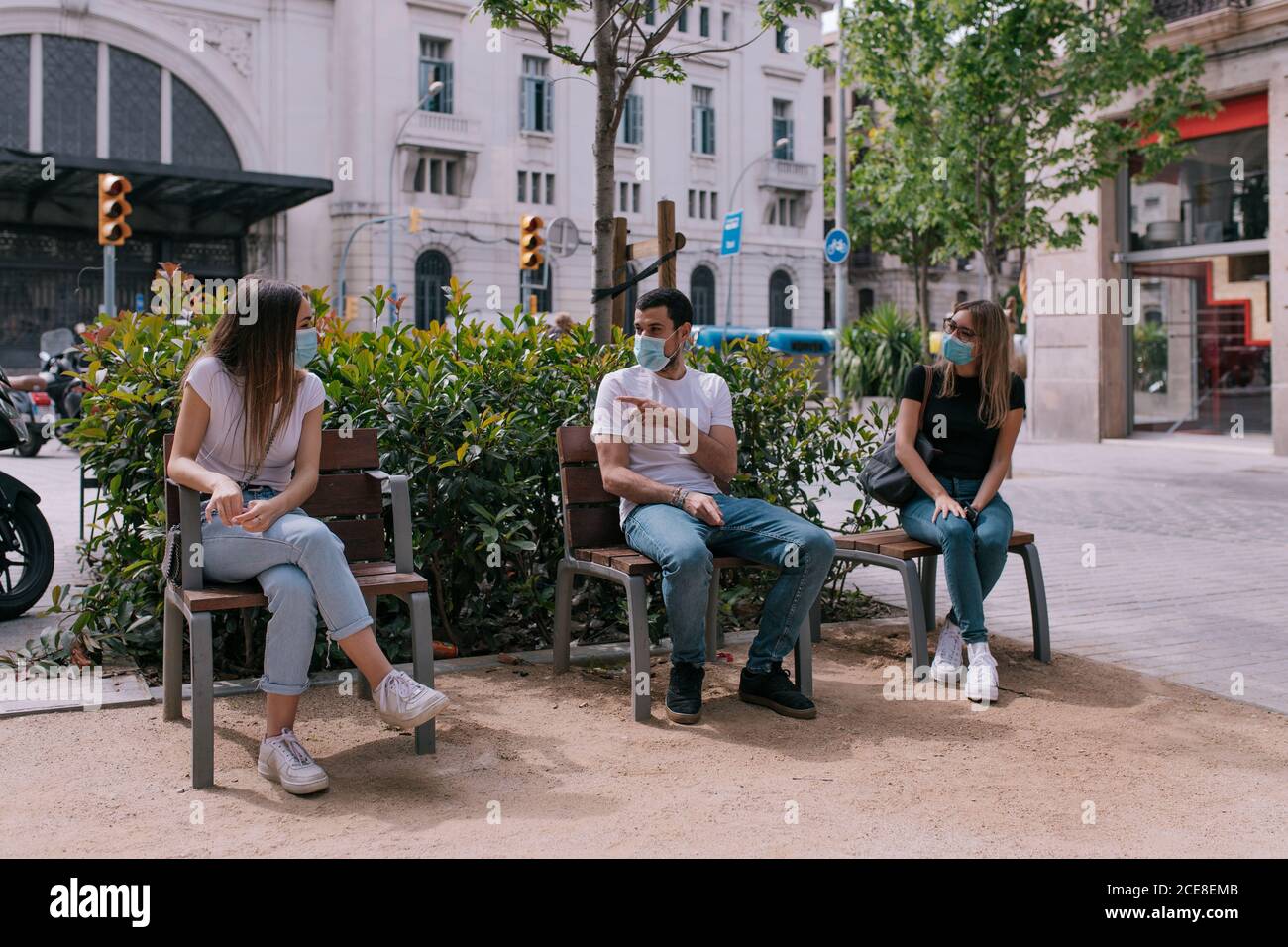 Tre amici che parlano e si divertono al parco all'aperto indossare maschere facciali e rispettare le distanze sociali durante una pandemia Foto Stock