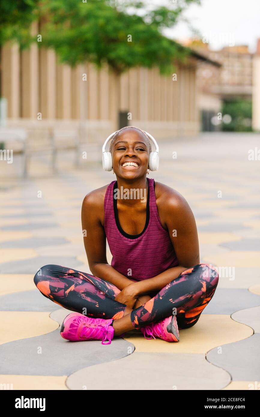 Atleta afroamericana positiva in abiti sportivi e cuffie seduta