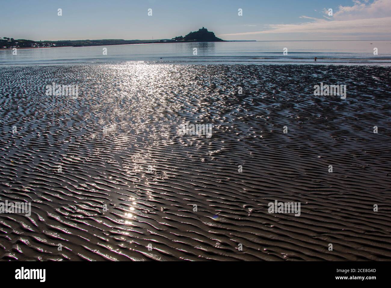 Sole che si riflette sulla spiaggia di sabbia a bassa marea con St Michael's Mount in lontananza Foto Stock