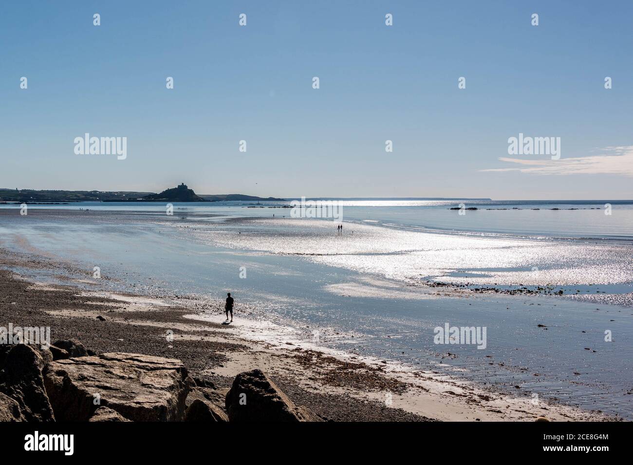 Persona che cammina lungo la spiaggia di Penzance verso St Michael's Mount a bassa marea Foto Stock