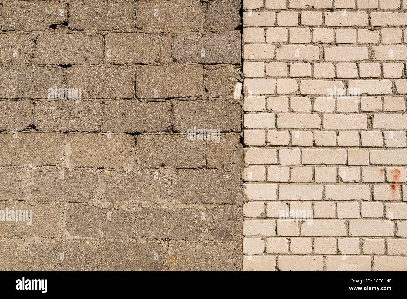 Cornice completa a parete con due sezioni di materiali diversi. Muro realizzato in parte da blocchi di cemento grigio e in parte da mattoni bianchi. Foto Stock