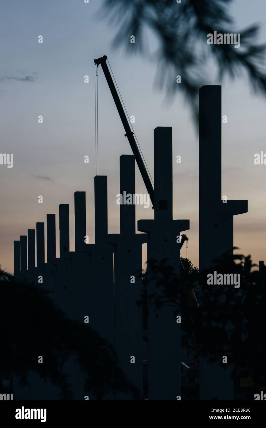 silhouette di cantiere con gru e colonne al tramonto Foto Stock