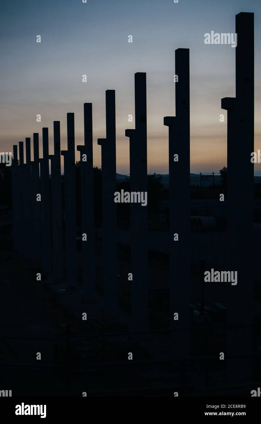 silhouette di cantiere con gru e colonne al tramonto Foto Stock