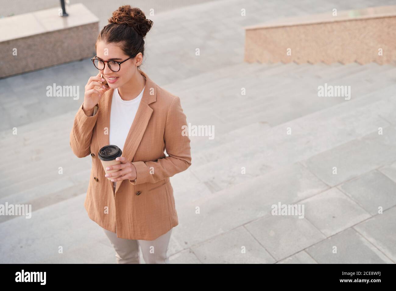 Sopra la vista di account manager in giacca bere caffè e. parlare con il cliente tramite telefono mentre si è in movimento Foto Stock