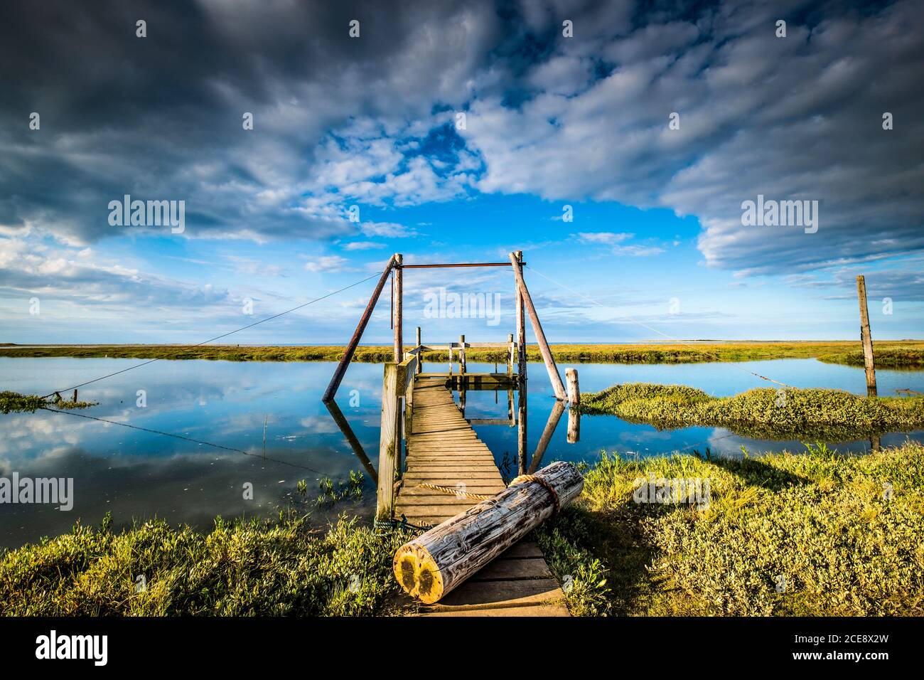 Un molo punta alla lontana palude di sale. Foto Stock