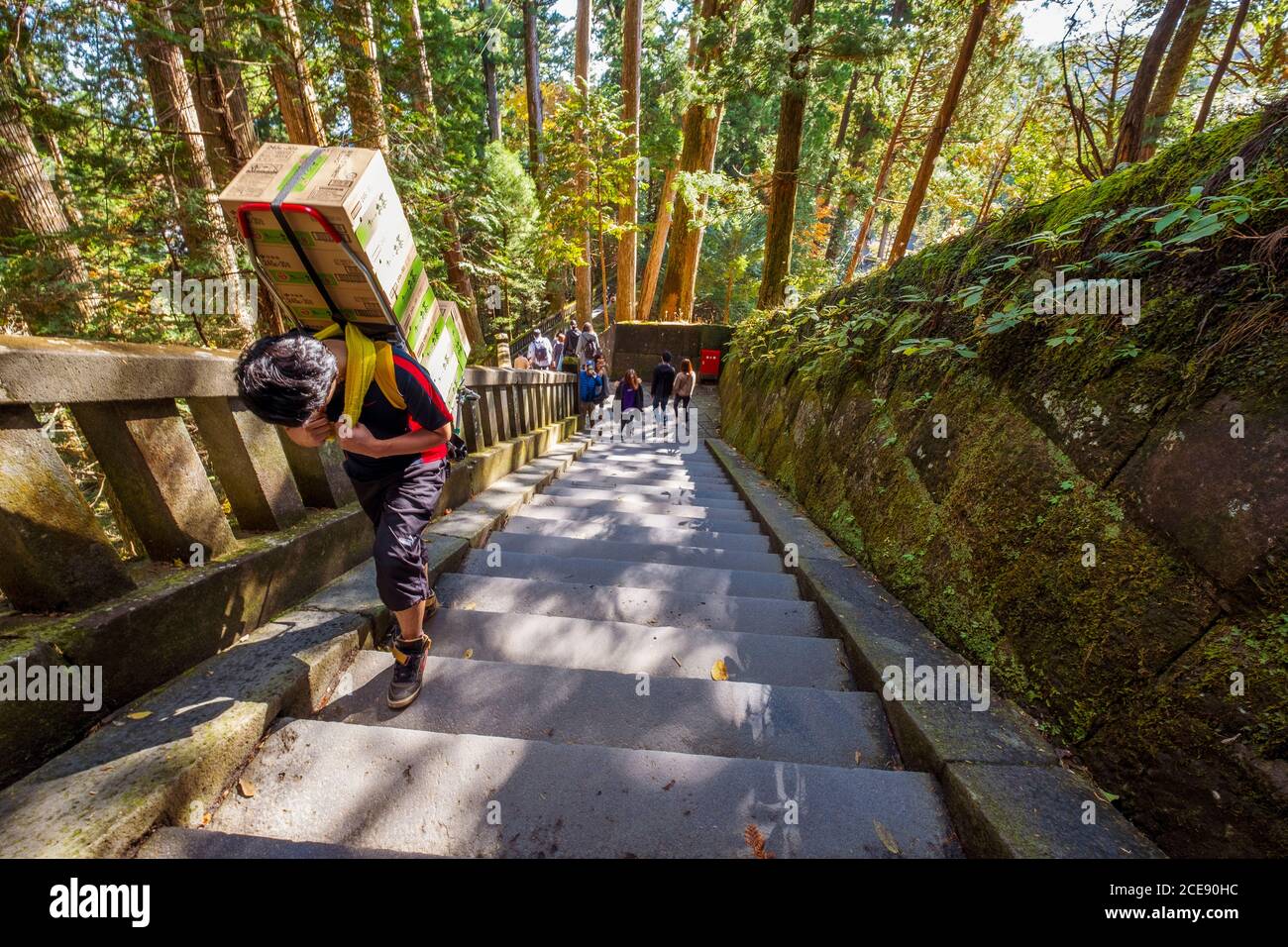 Un uomo duro che lavora consegnando le scatole sulla parte superiore di un tempiale in Nikko in Giappone. Foto Stock