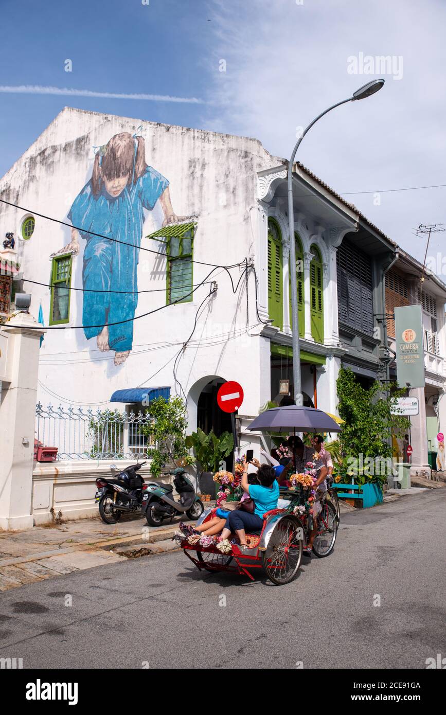 Georgetown, Penang/Malaysia - Agosto 14 2016: Piccola ragazza in Blue Mural a Muntri Street. Il passeggero in risciò scatta una foto. Foto Stock