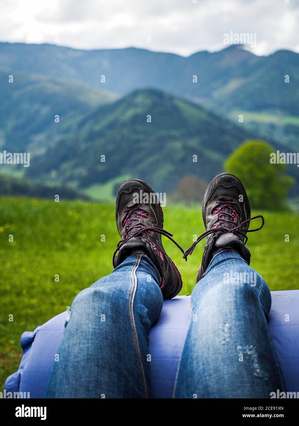 Ragazza in scarpe da trekking e jeans blu che si riposa e gode di una  splendida vista sulle montagne Foto stock - Alamy