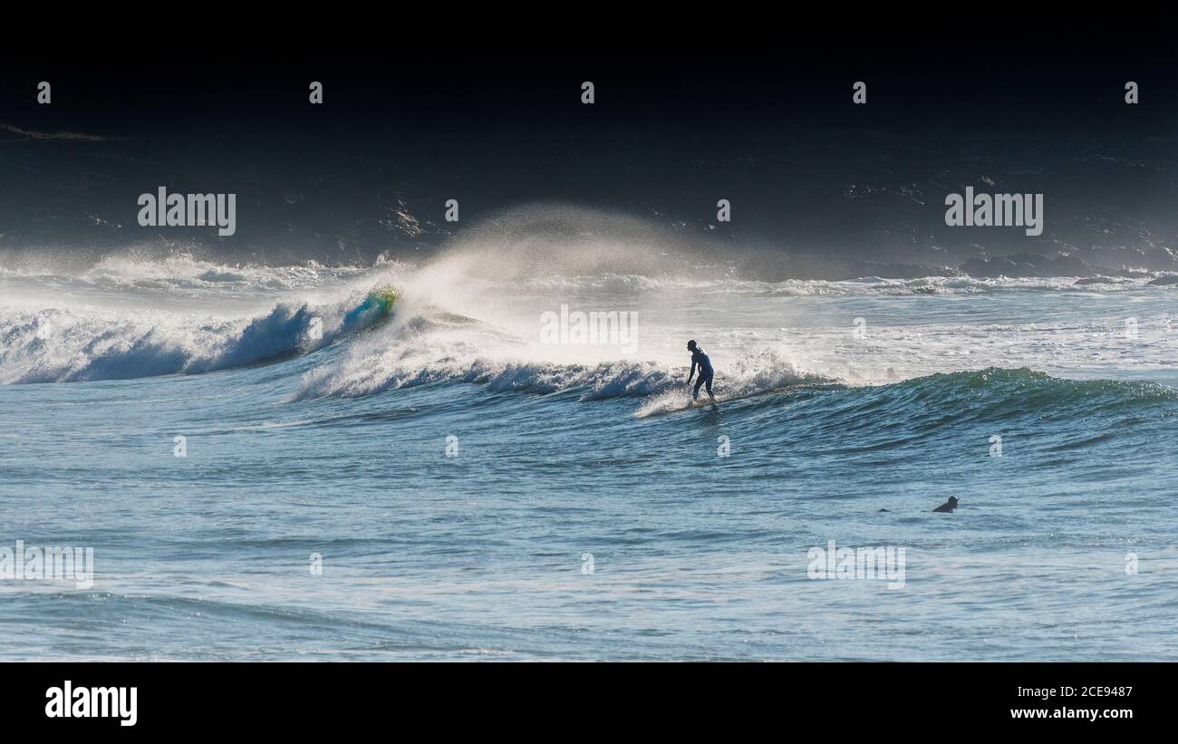 Un'immagine panoramica di un surfista che cavalcerà un'onda al South Fistral a Newquay in Cornovaglia. Foto Stock